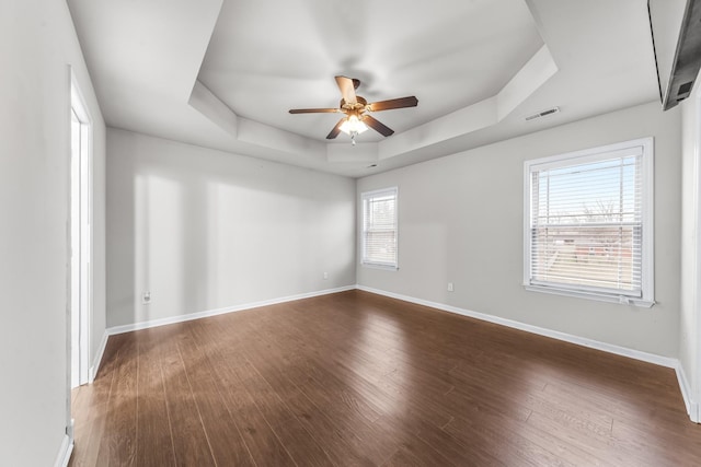 unfurnished room with dark wood-type flooring, ceiling fan, and a tray ceiling