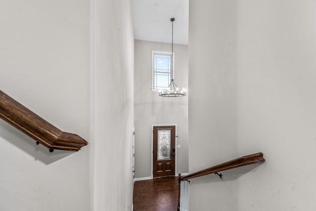 stairs with hardwood / wood-style flooring, a towering ceiling, and an inviting chandelier