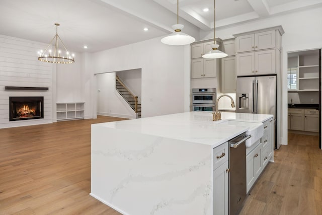 kitchen with pendant lighting, gray cabinetry, a large island, light hardwood / wood-style floors, and light stone countertops