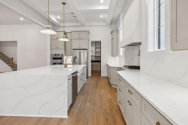 kitchen with pendant lighting, appliances with stainless steel finishes, premium range hood, coffered ceiling, and light stone countertops