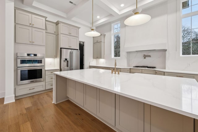 kitchen featuring light stone counters, backsplash, decorative light fixtures, and appliances with stainless steel finishes