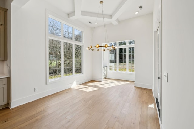 unfurnished dining area featuring an inviting chandelier, beamed ceiling, a high ceiling, coffered ceiling, and light wood-type flooring