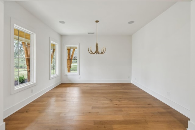 unfurnished dining area with a chandelier, a healthy amount of sunlight, and light wood-type flooring