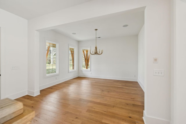 spare room featuring a notable chandelier and hardwood / wood-style flooring