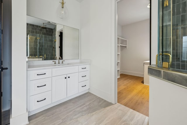 bathroom featuring vanity, wood-type flooring, and a tile shower