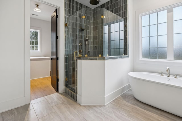 bathroom with hardwood / wood-style flooring and shower with separate bathtub