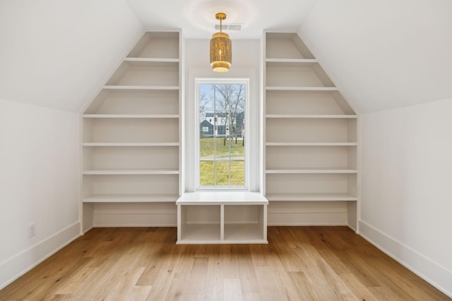 additional living space with vaulted ceiling, hardwood / wood-style floors, and built in shelves