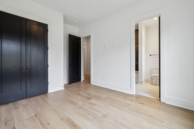 unfurnished bedroom with connected bathroom, light hardwood / wood-style floors, and a closet