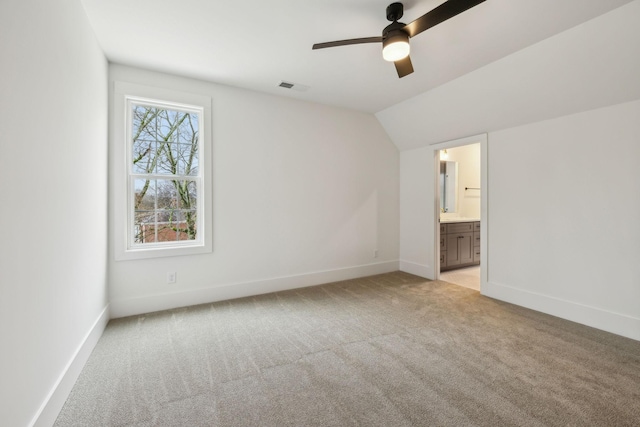 unfurnished bedroom with ensuite bathroom, lofted ceiling, light colored carpet, and ceiling fan