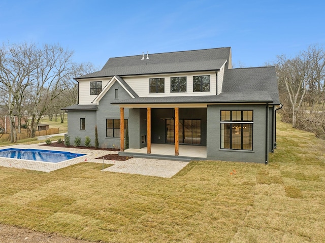 rear view of house with a patio area, a covered pool, and a lawn