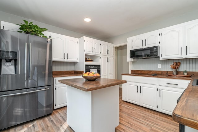 kitchen featuring white cabinets, wooden counters, a center island, and black appliances