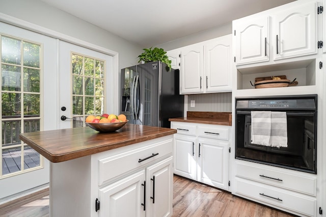 kitchen with butcher block counters, white cabinetry, a center island, stainless steel fridge with ice dispenser, and oven