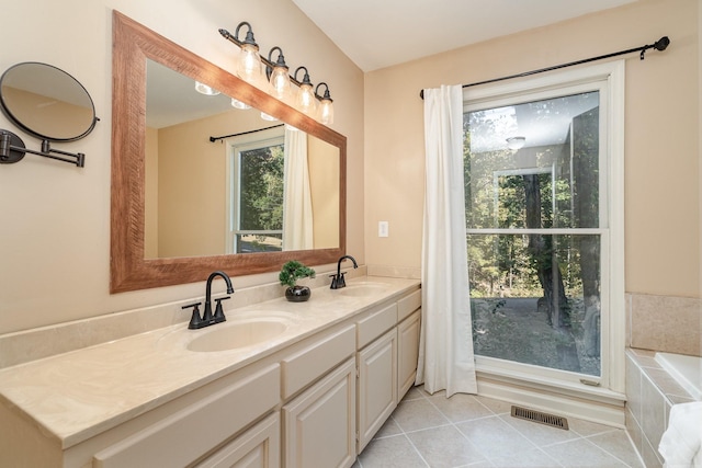 bathroom with tile patterned flooring, vanity, and tiled bath