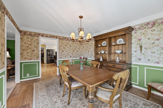 dining area featuring hardwood / wood-style flooring, ornamental molding, and a chandelier