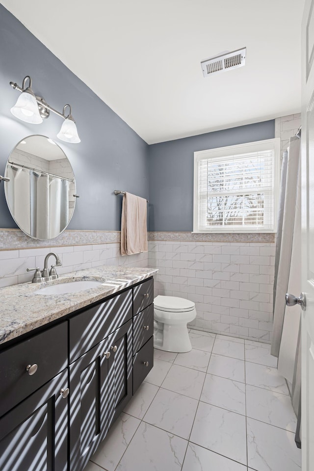 bathroom featuring vanity, tile walls, and toilet