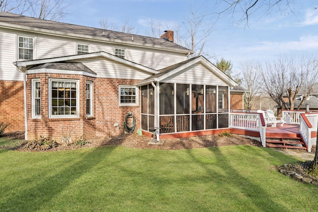 rear view of property with a wooden deck, a sunroom, and a lawn