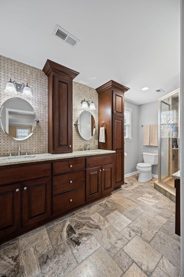 bathroom featuring vanity, toilet, a shower with shower door, and decorative backsplash