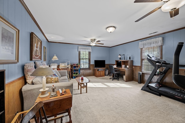 living room with crown molding, light colored carpet, ceiling fan, and wood walls