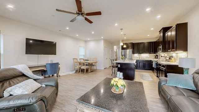 living room with ceiling fan, sink, and light wood-type flooring