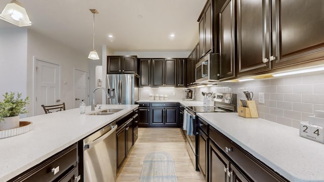 kitchen featuring sink, backsplash, stainless steel appliances, dark brown cabinetry, and decorative light fixtures