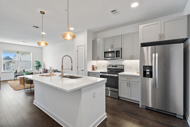 kitchen featuring appliances with stainless steel finishes, a kitchen island with sink, pendant lighting, and gray cabinetry