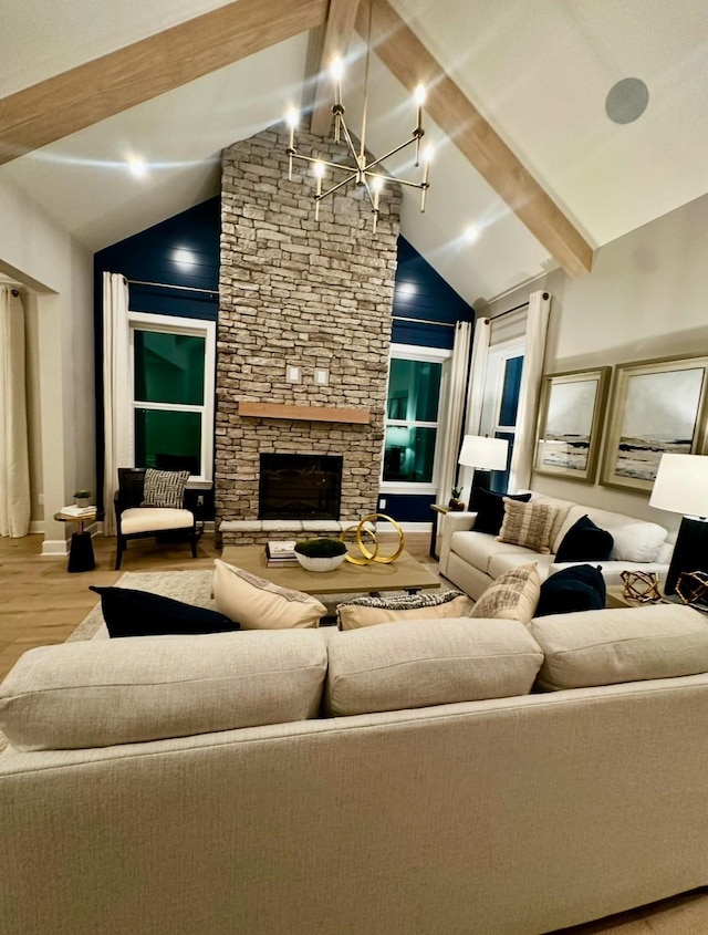 living room with light hardwood / wood-style flooring, high vaulted ceiling, a notable chandelier, a stone fireplace, and beamed ceiling