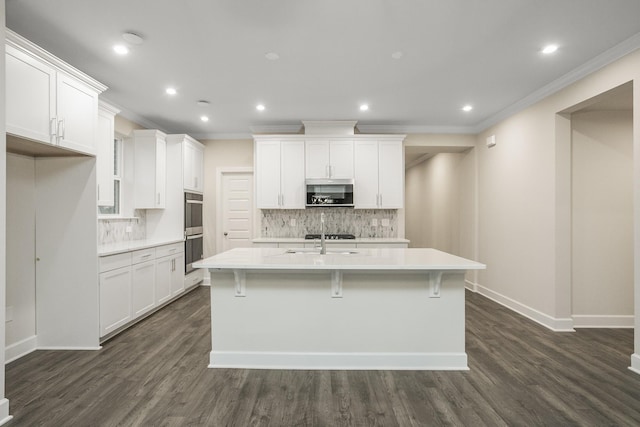 kitchen featuring white cabinetry, an island with sink, and stainless steel double oven