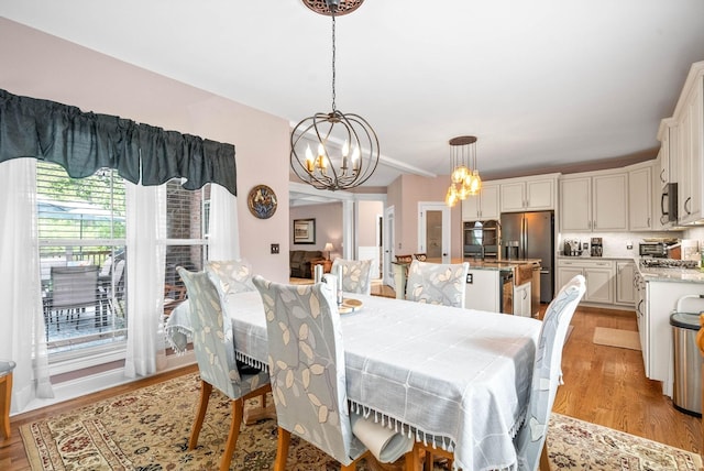 dining room with light hardwood / wood-style floors and a notable chandelier