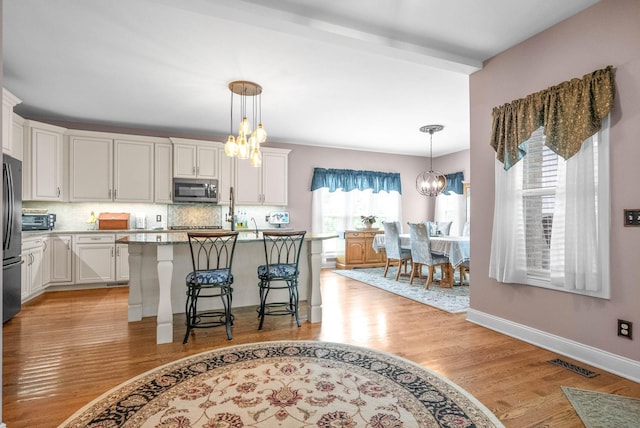 kitchen featuring a breakfast bar, appliances with stainless steel finishes, a center island, a notable chandelier, and white cabinets