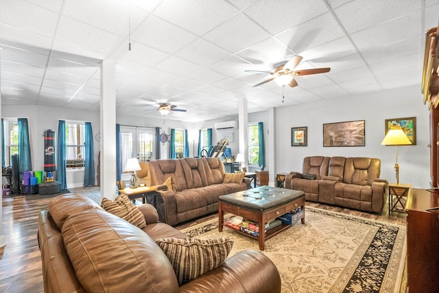 living room with french doors, a paneled ceiling, a wall mounted AC, ceiling fan, and hardwood / wood-style floors