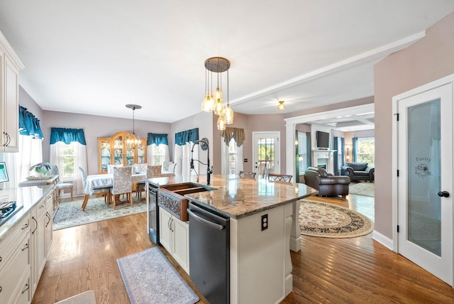 kitchen with a chandelier, dishwasher, an island with sink, pendant lighting, and white cabinets