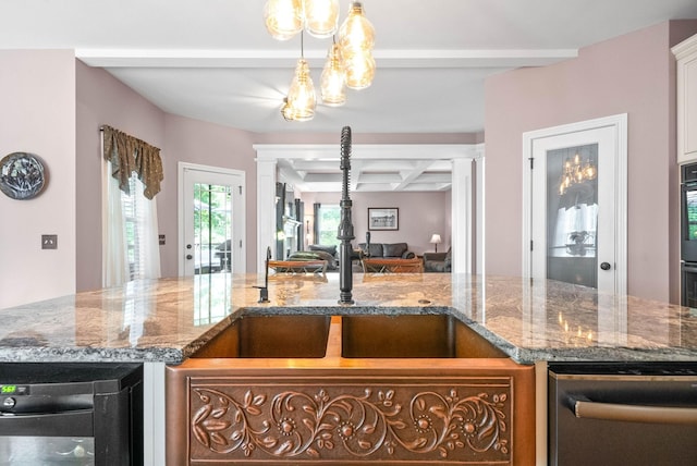 kitchen featuring beamed ceiling, coffered ceiling, light stone counters, and ornate columns