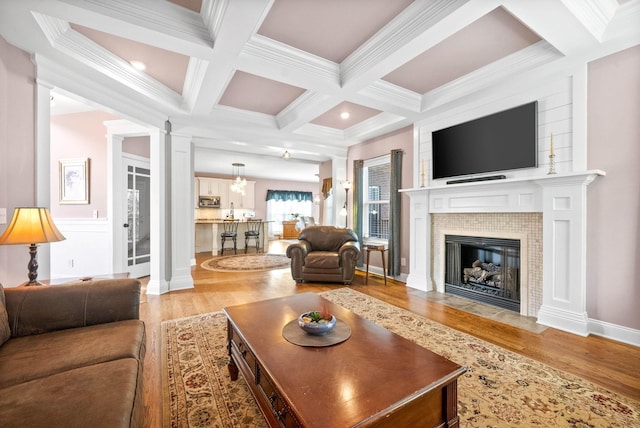 living room with beam ceiling, wood-type flooring, and a tile fireplace