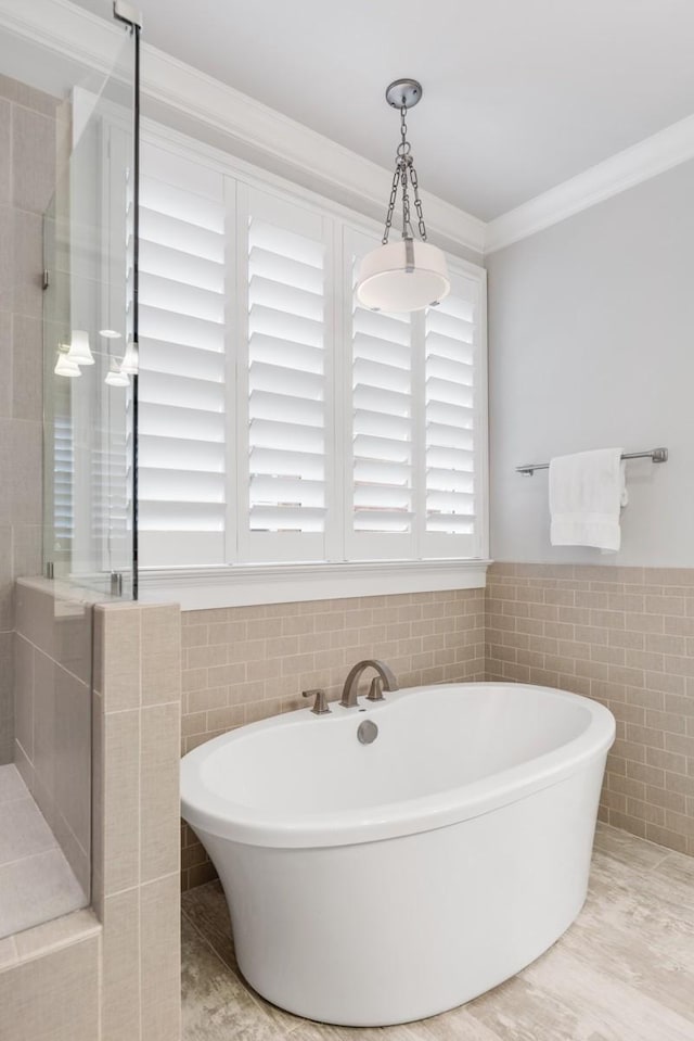 bathroom featuring crown molding, shower with separate bathtub, and tile walls