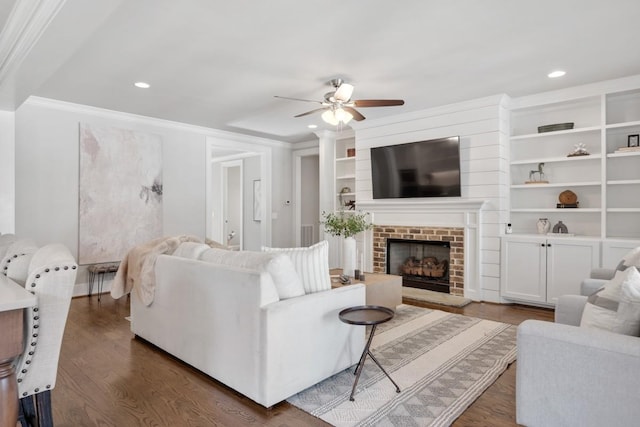 living room with a brick fireplace, ornamental molding, dark hardwood / wood-style floors, and ceiling fan