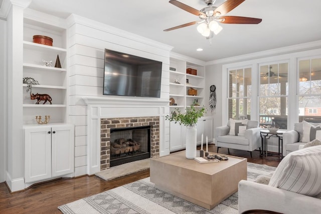 living room with ornamental molding, built in features, a fireplace, and dark hardwood / wood-style flooring