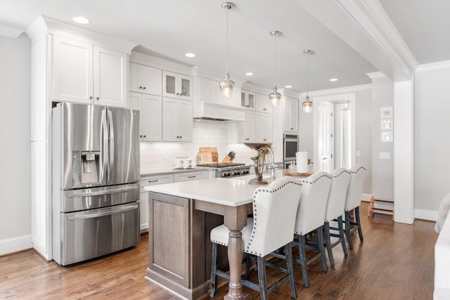 kitchen featuring stainless steel refrigerator with ice dispenser, decorative light fixtures, ornamental molding, a kitchen island with sink, and white cabinets