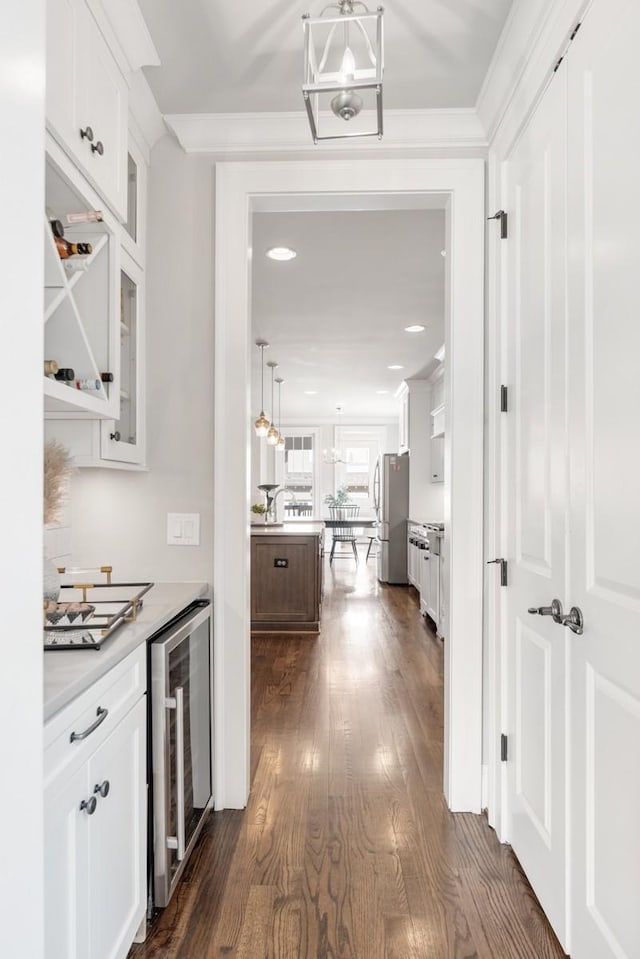 interior space with dark wood-type flooring, ornamental molding, beverage cooler, and a notable chandelier