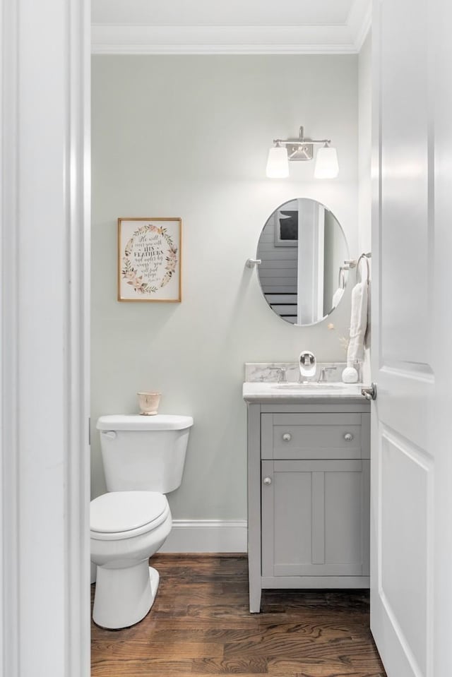 bathroom with hardwood / wood-style flooring, ornamental molding, vanity, and toilet