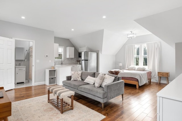 bedroom featuring wood-type flooring, stainless steel fridge, and multiple windows