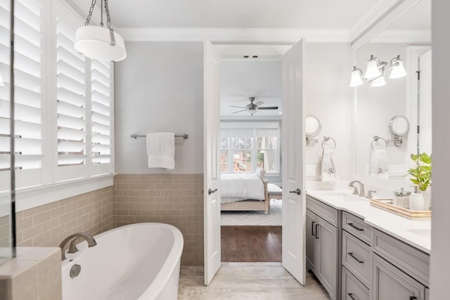 bathroom with a bathing tub, ornamental molding, tile walls, and vanity