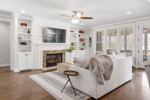 living room featuring a brick fireplace, dark hardwood / wood-style floors, built in features, and ceiling fan