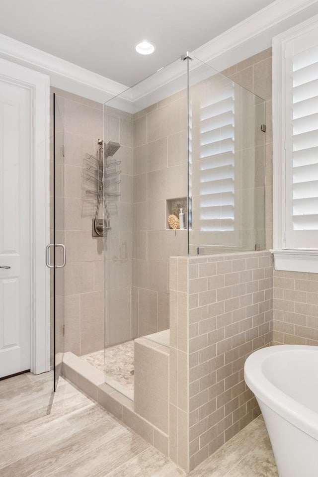 bathroom featuring independent shower and bath, ornamental molding, hardwood / wood-style floors, and tile walls