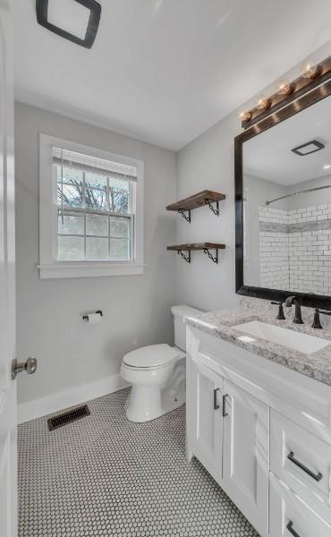 bathroom featuring vanity, walk in shower, and toilet