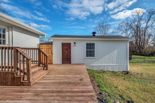 exterior space with a wooden deck and a front lawn