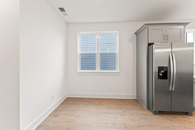 kitchen with a wealth of natural light, gray cabinetry, light hardwood / wood-style floors, and stainless steel fridge with ice dispenser