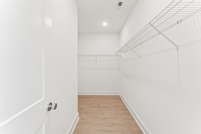 walk in closet with light hardwood / wood-style floors