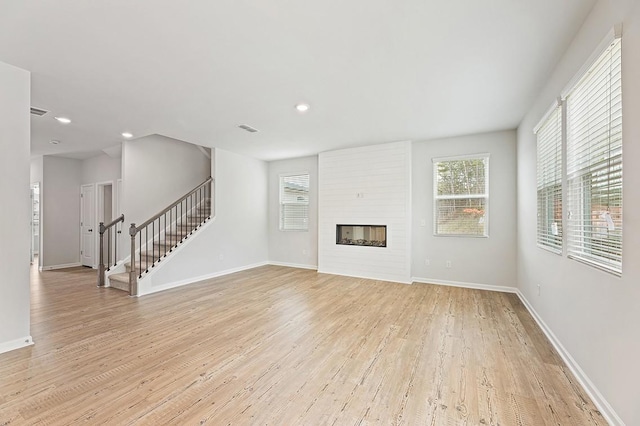 unfurnished living room featuring a large fireplace and light hardwood / wood-style floors