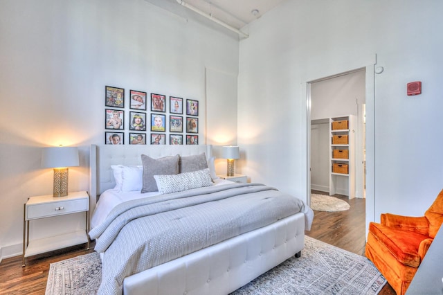 bedroom with a towering ceiling, dark hardwood / wood-style floors, and a walk in closet