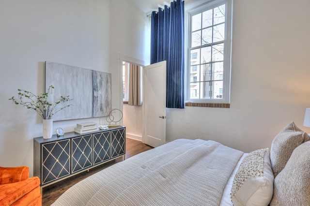 bedroom with multiple windows and dark hardwood / wood-style floors